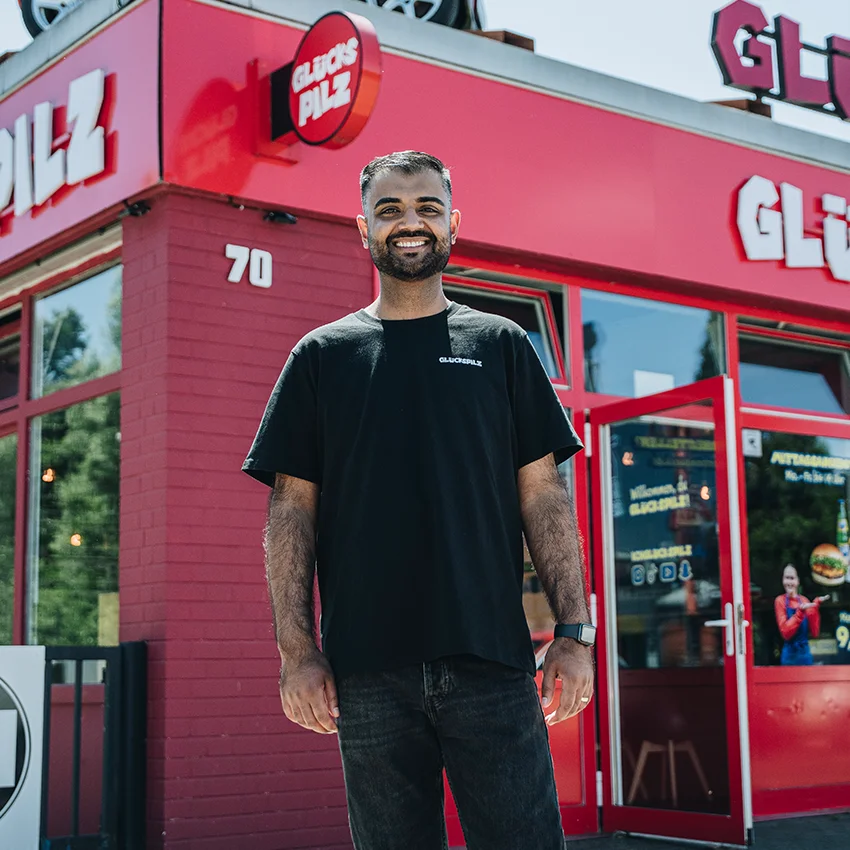 Der Gründer der Burgerkette Glückspilz Umer Butt steht vor einer Filiale