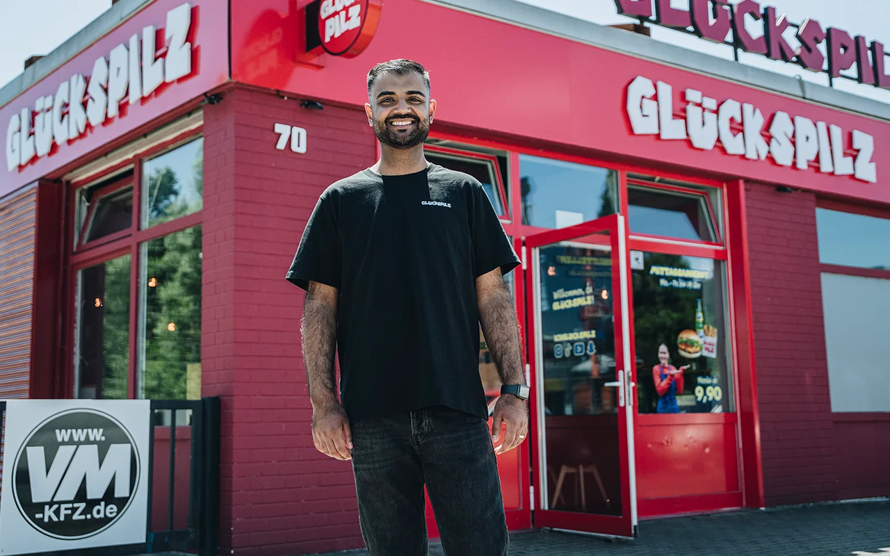 Der Gründer der Burgerkette Glückspilz Umer Butt steht vor einer Filiale