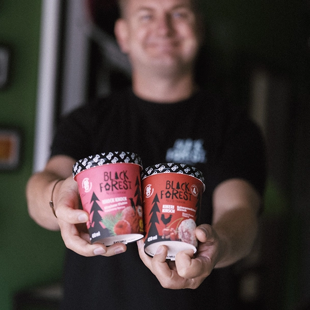 Matthias Rothacher mit zwei Bechern des Speiseeis von Black Forest Ice Cream