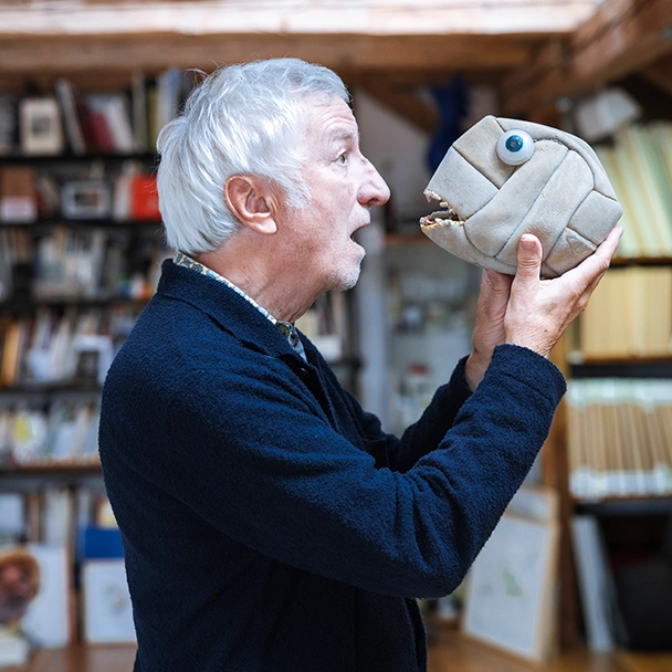 Cartoonist Peter Gaymann redet mit einem aufgeschnittenen Volleyball