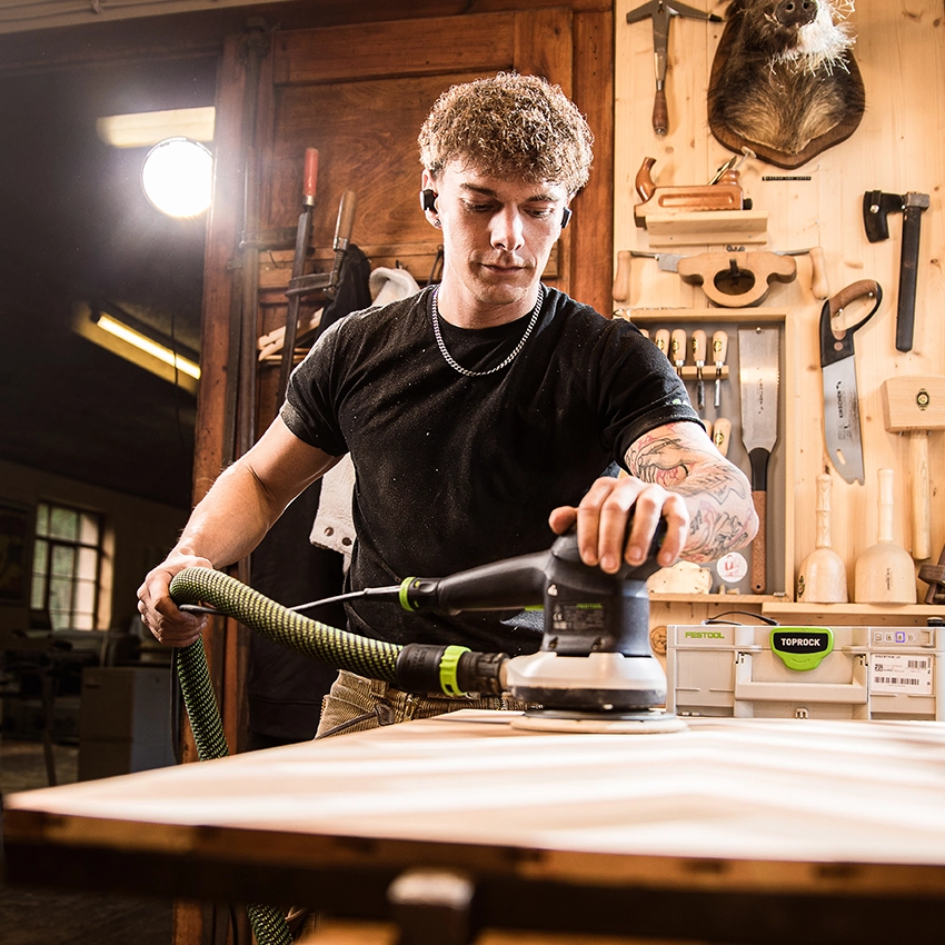 Handwerker Ben Berger schleift eine Holzplatte