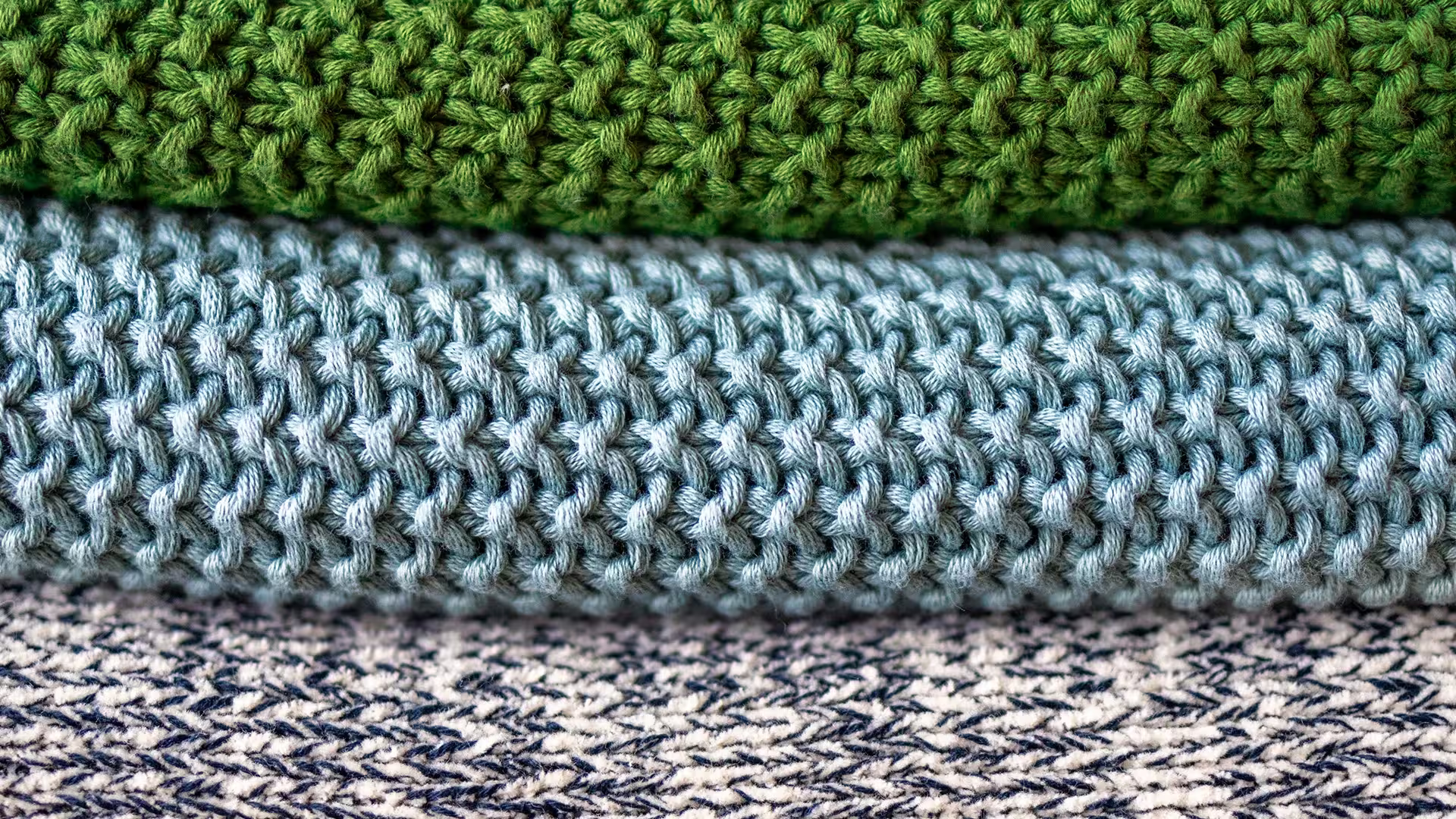 Eine Abbildung von drei zusammengelegten Strickpullover