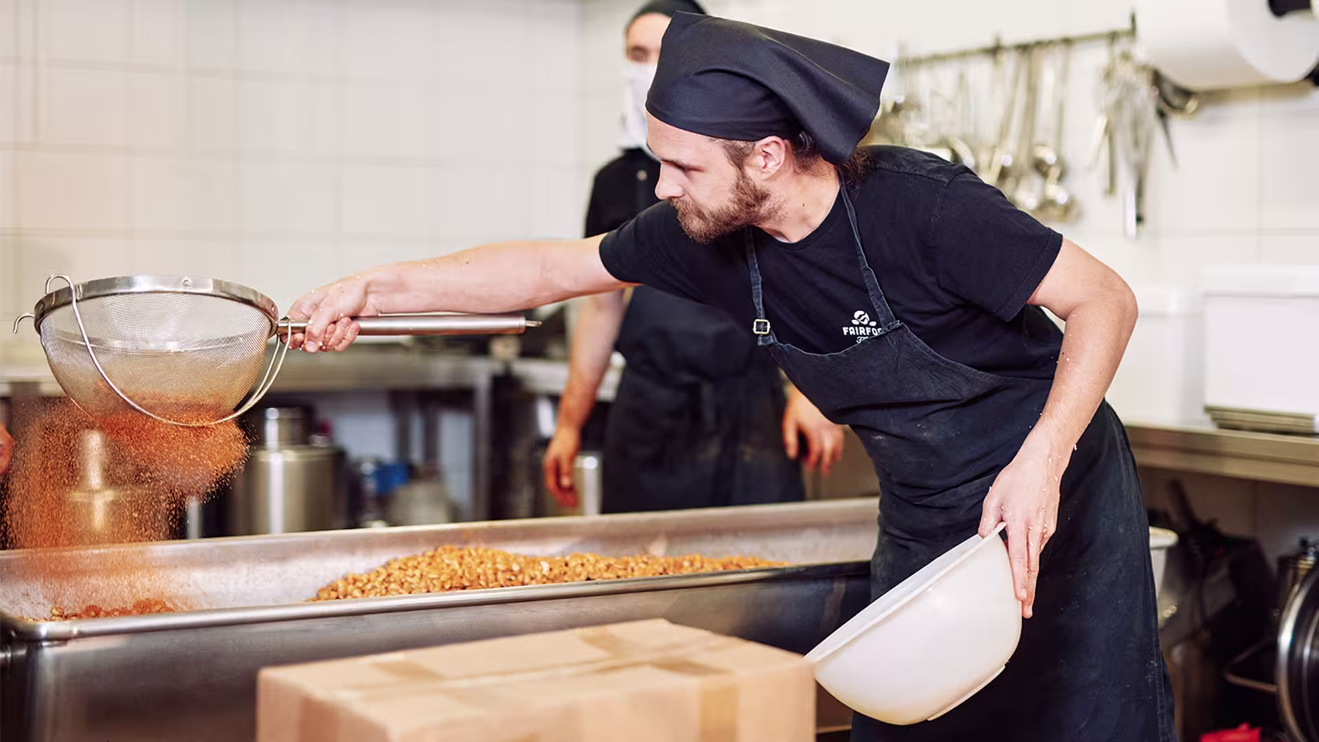 Ein Gründer von fairfood Freiburg beim Würzen von Nüssen - Beitragsbild von Lexware Tell Your Story
