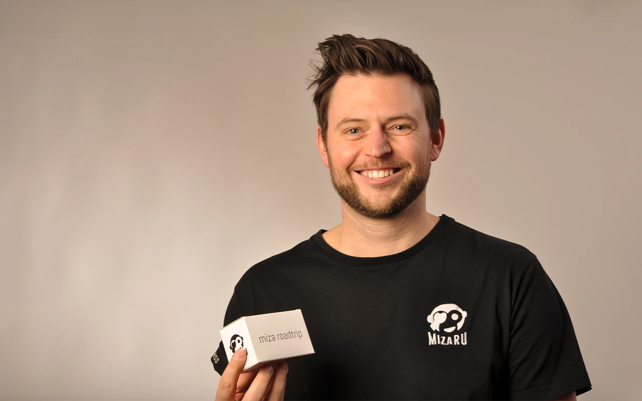 Samuel hält sein Produkt in der Hand und lächelt in die Kamera.