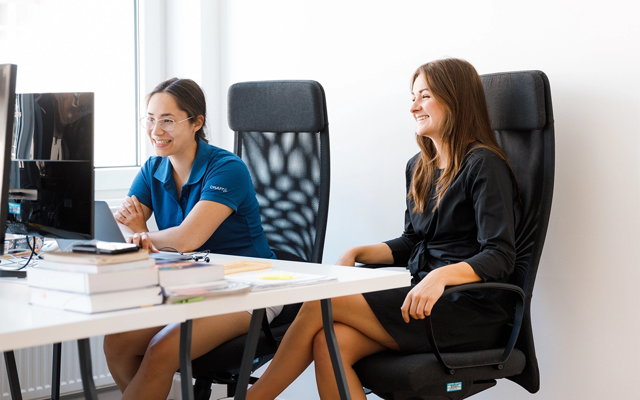 Zwei am Schreibtisch sitzende Frauen, die auf Bildschirm schauen- Beitragsbild von Lexware Tell Your Story