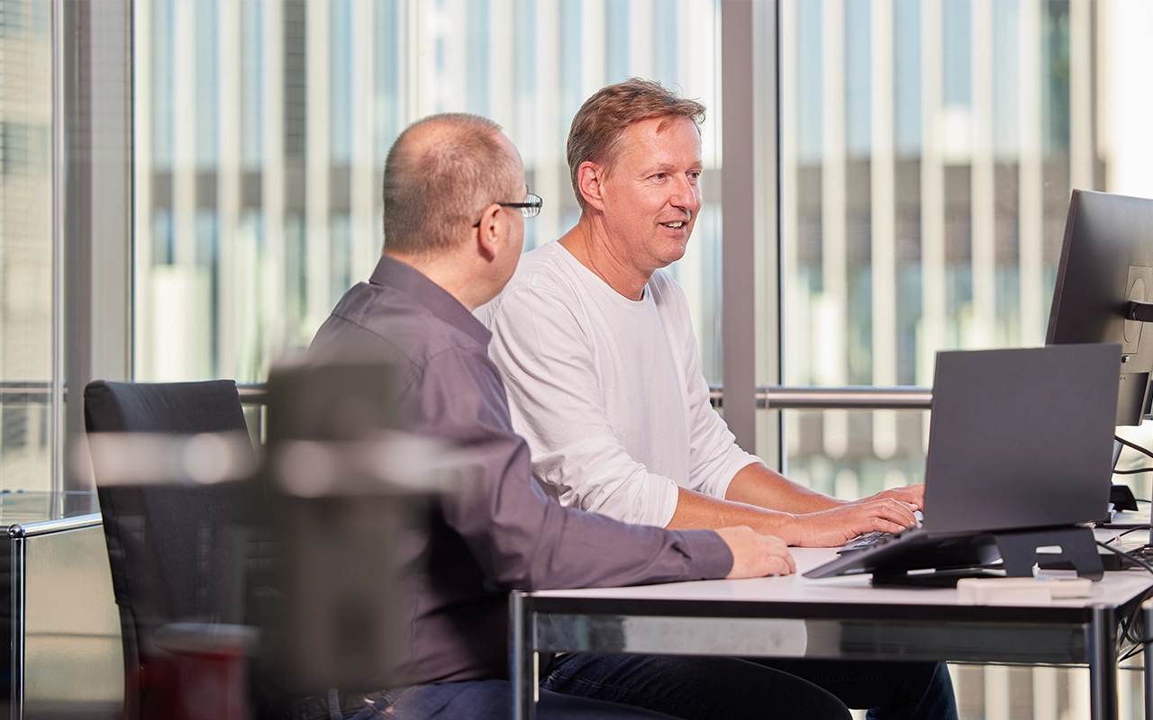Zwei Männer am Schreibtisch vor PC- Beitragsbild von Lexware Tell Your Story