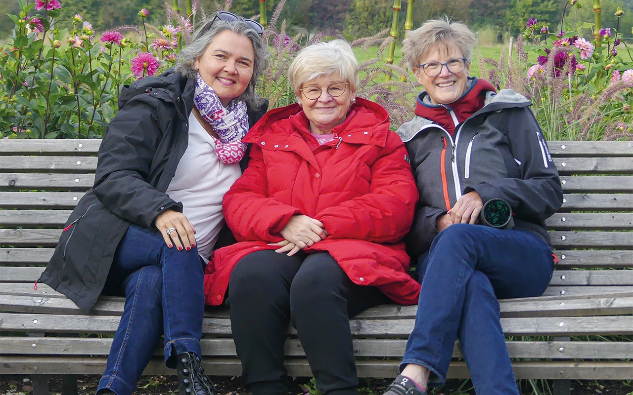 Drei Frauen sitzen im Freien auf einer Bank