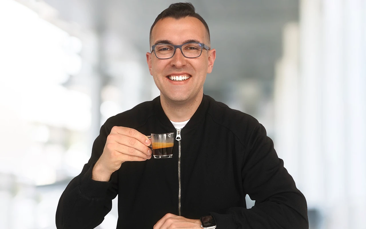 Fabian Walter lächelt und hält einen Espresso in der Hand