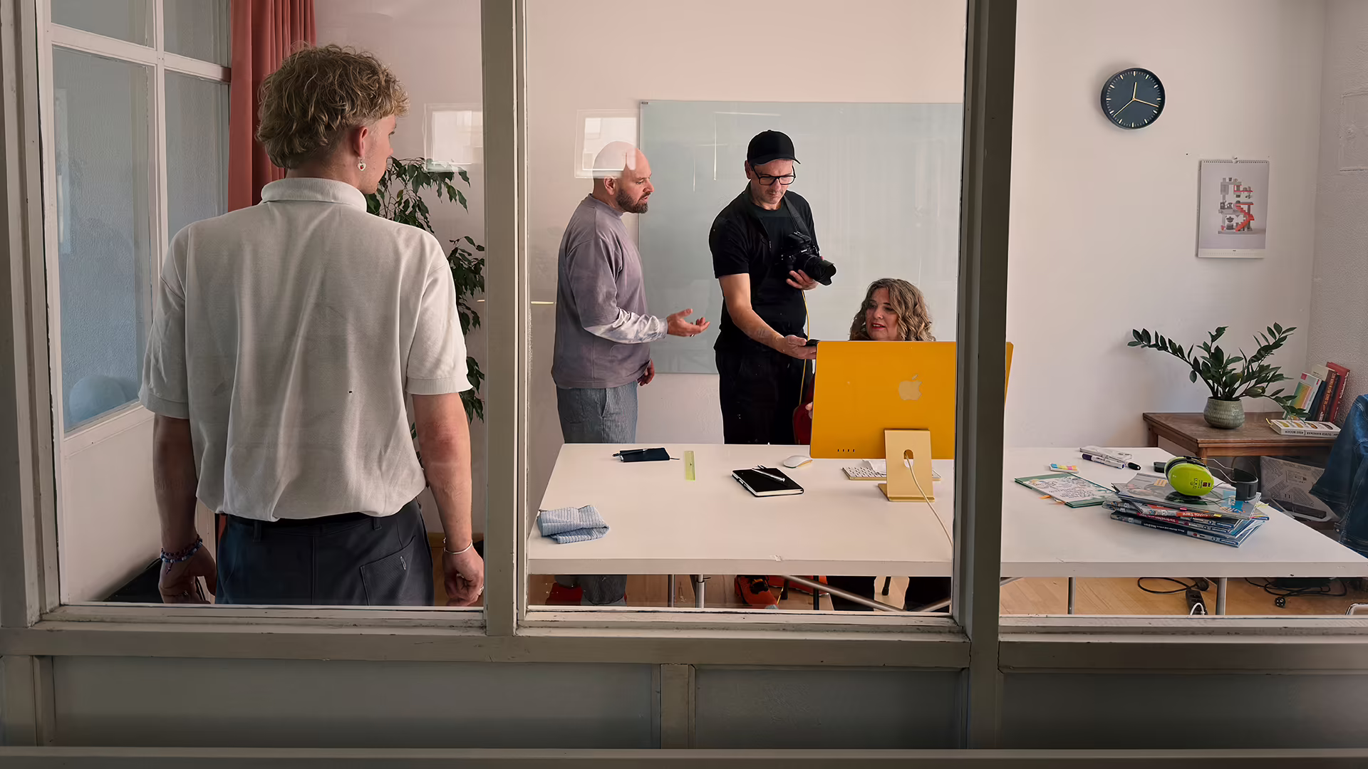 Christoph Duepper fotografiert eine Frau am Schreibtisch, gesehen durch eine Bürofensterwand.