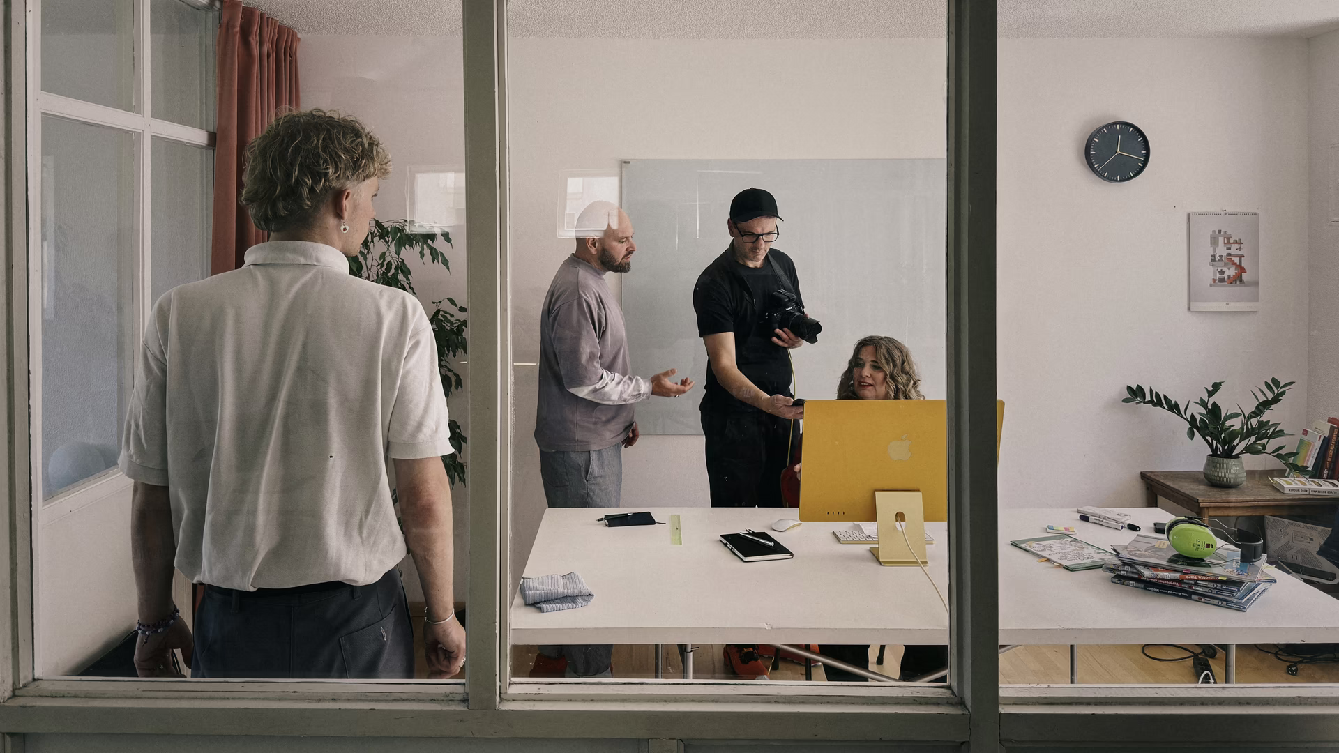 Christoph Duepper fotografiert eine Frau am Schreibtisch, gesehen durch eine Bürofensterwand.