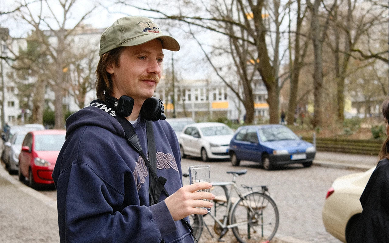 Filmregisseur Severin Werner steht auf der Straße mit einem Glas Wasser in der Hand.