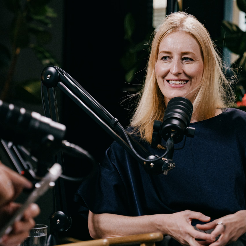 Julia Bösch lächelt während der Podcast-Aufnahme hinter dem Mikrofon.
