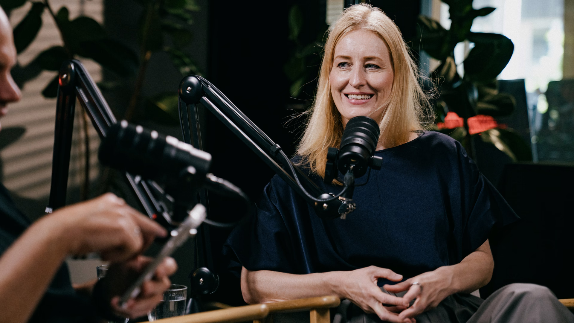 Julia Bösch lächelt während der Podcast-Aufnahme hinter dem Mikrofon.