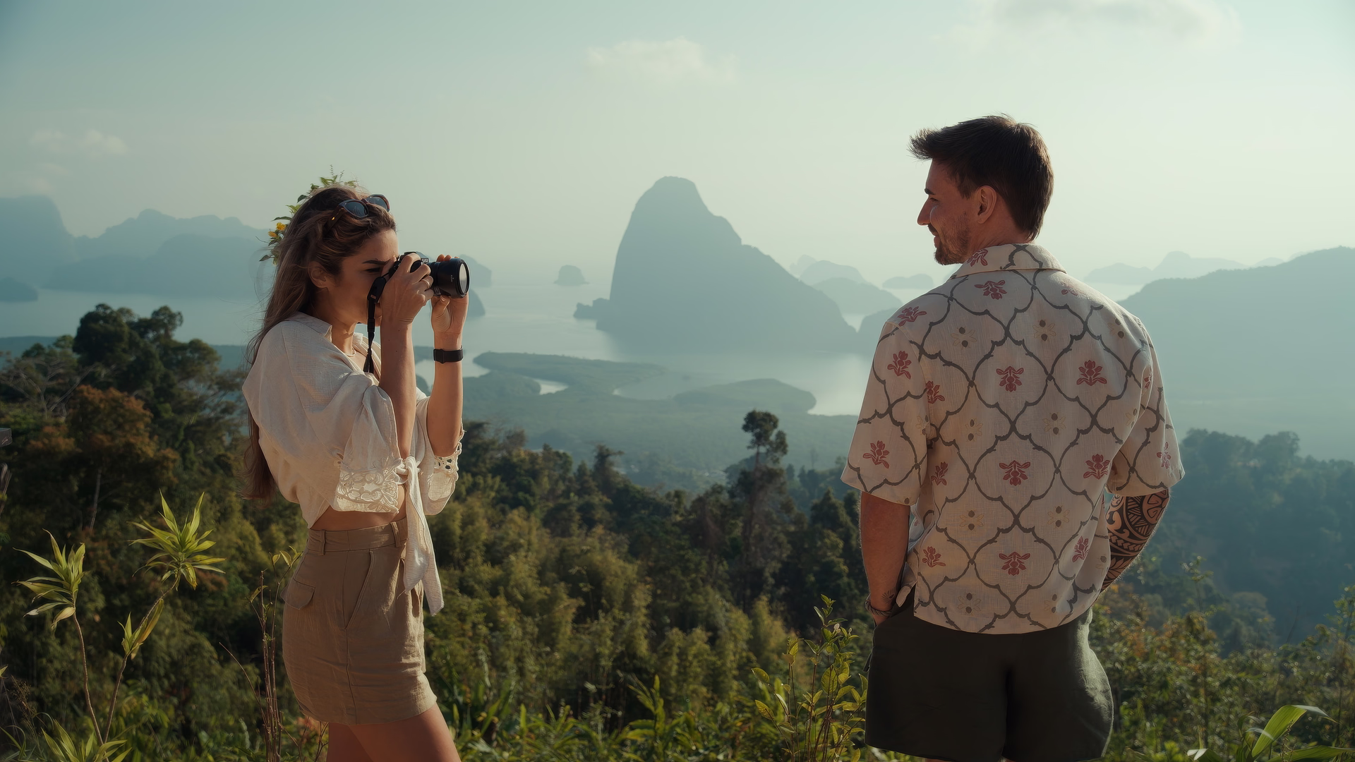 Nathalie Naceur fotografiert Sören Jeßner an einem Aussichtspunkt über einer Bucht mit Kalksteinfelsen und Dschungel.