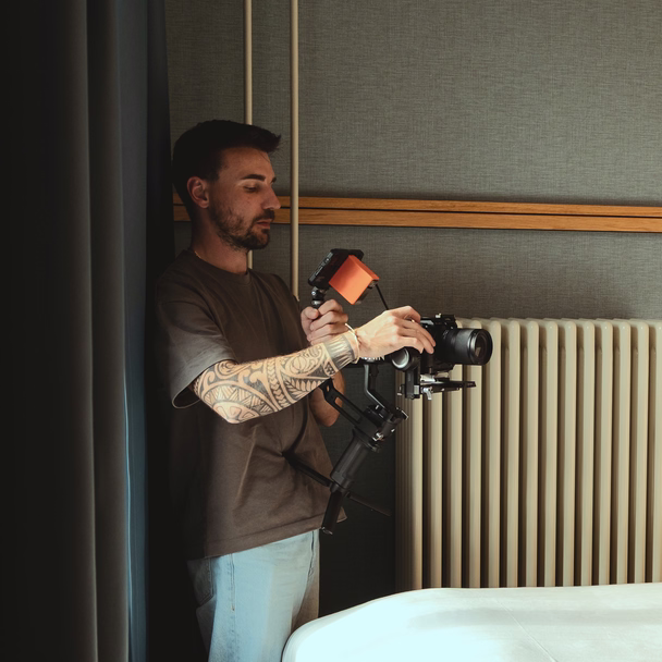 Sören Jeßner filmt mit Kamera und Gimbal in einem Hotelzimmer.