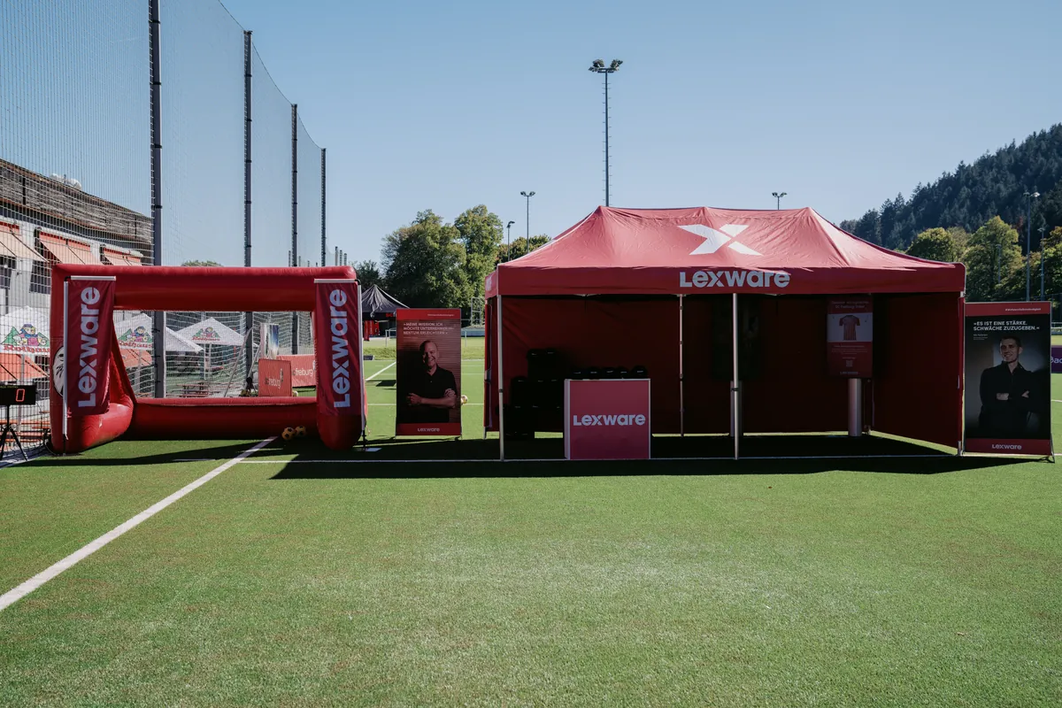 Der Lexware-Stand auf dem Kunstrasen: links die aufblasbare Torwand, rechts der rote Pavillon mit Tresen und Aufstellern.