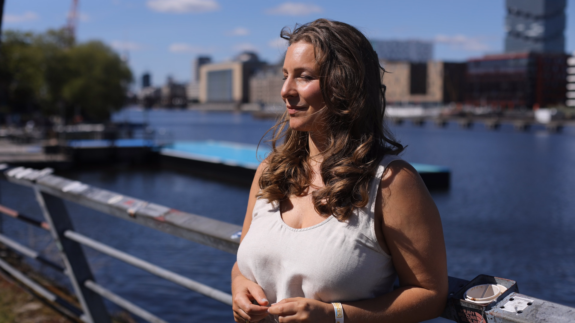 Sarah-Lisa Besemer steht an einem Geländer an der Spree in Berlin und blickt zur Seite.
