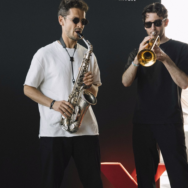 Kamil Khusyainov spielt Saxophon, neben ihm ein Trompeter, beide in Sonnenbrillen.