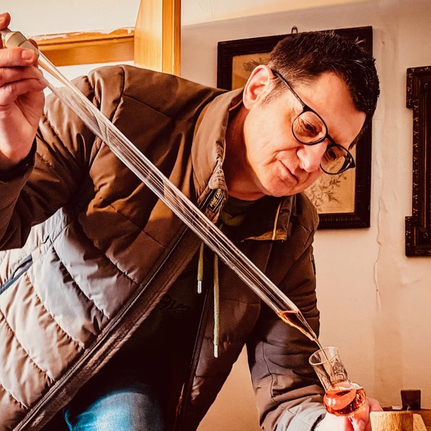 Mathias Gerstner zieht mit einem Glasheber eine Probe aus einem Holzfass.