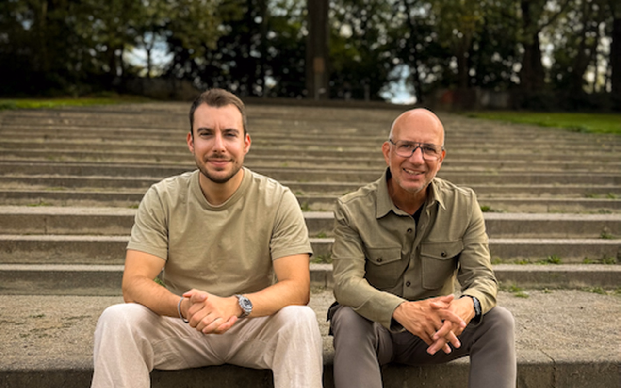 Christoph Bergemann (links) und sein Vater Frank sitzen nebeneinander auf einer Steintreppe im Park.