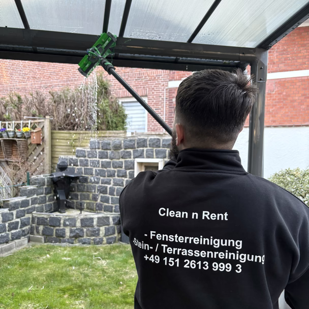 Mirko Bilić putzt das Glasdach einer Terrassenüberdachung, auf seiner Jacke steht Clean n Rent.