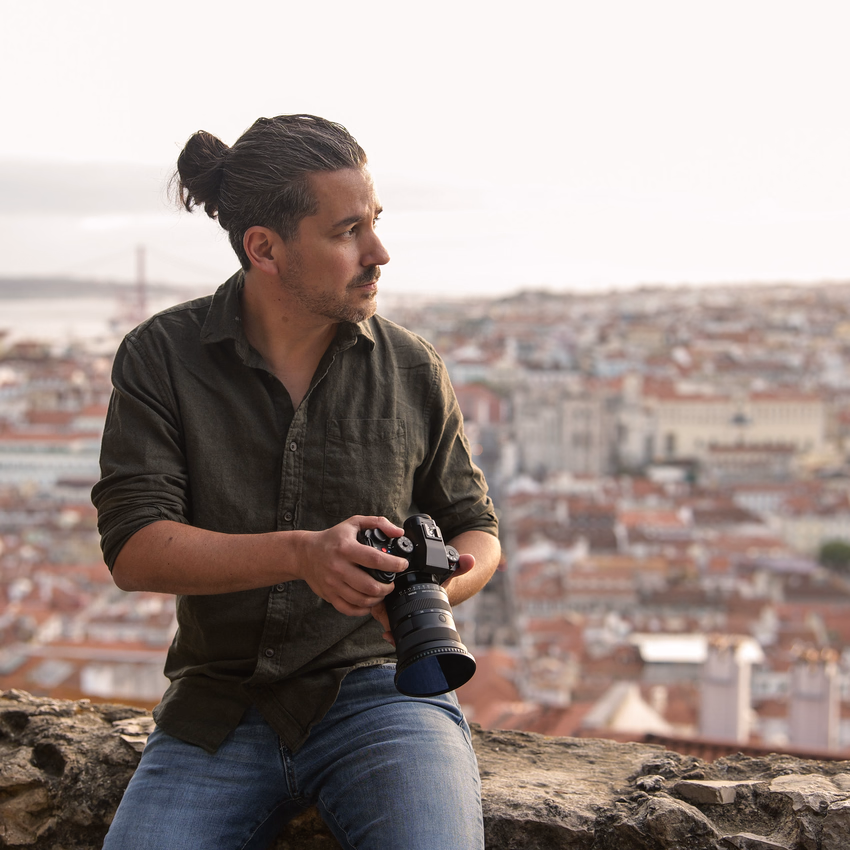 Andreas Abb mit Kamera in der Hand vor dem Häusermeer von Lissabon.