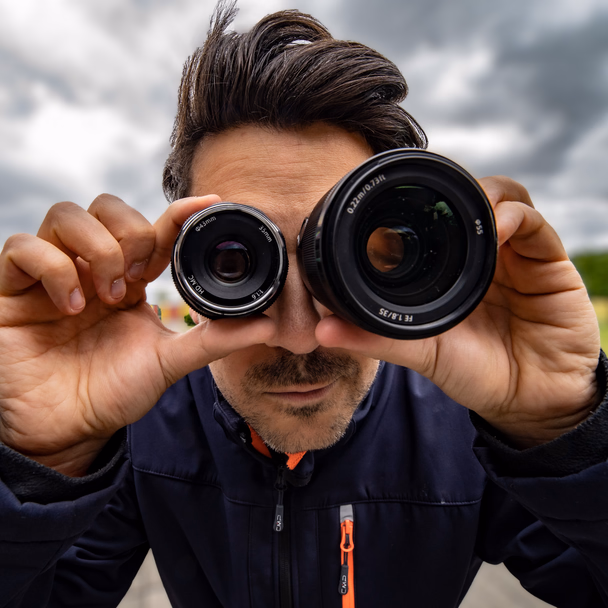 Andreas Abb hält sich zwei Kameraobjektive wie ein Fernglas vor die Augen.