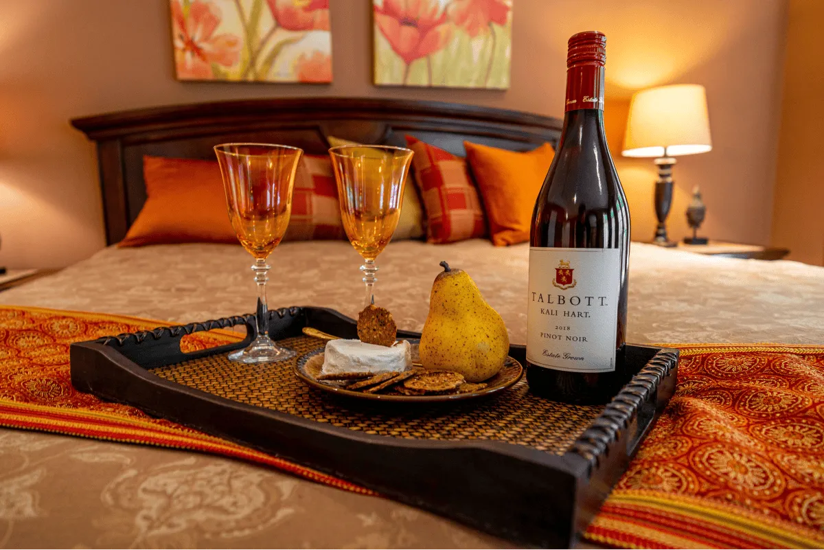 A bottle of wine and charcuterie on the master bed, the essentials for a romantic evening in the master suite.