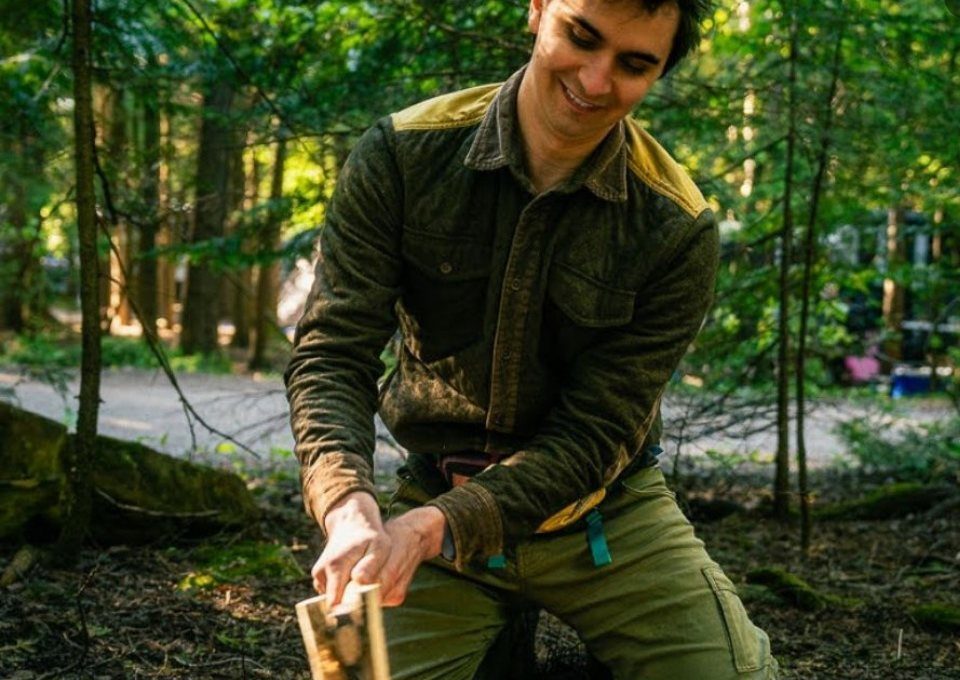 A participant carving a piece of wood with a knife