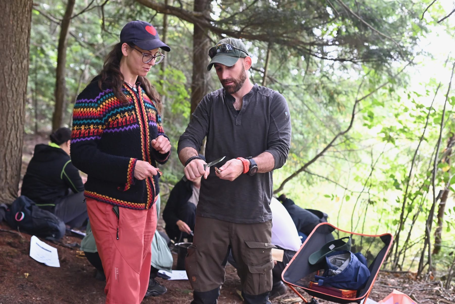 Kyle demonstrating knife work to a course participant in the forest