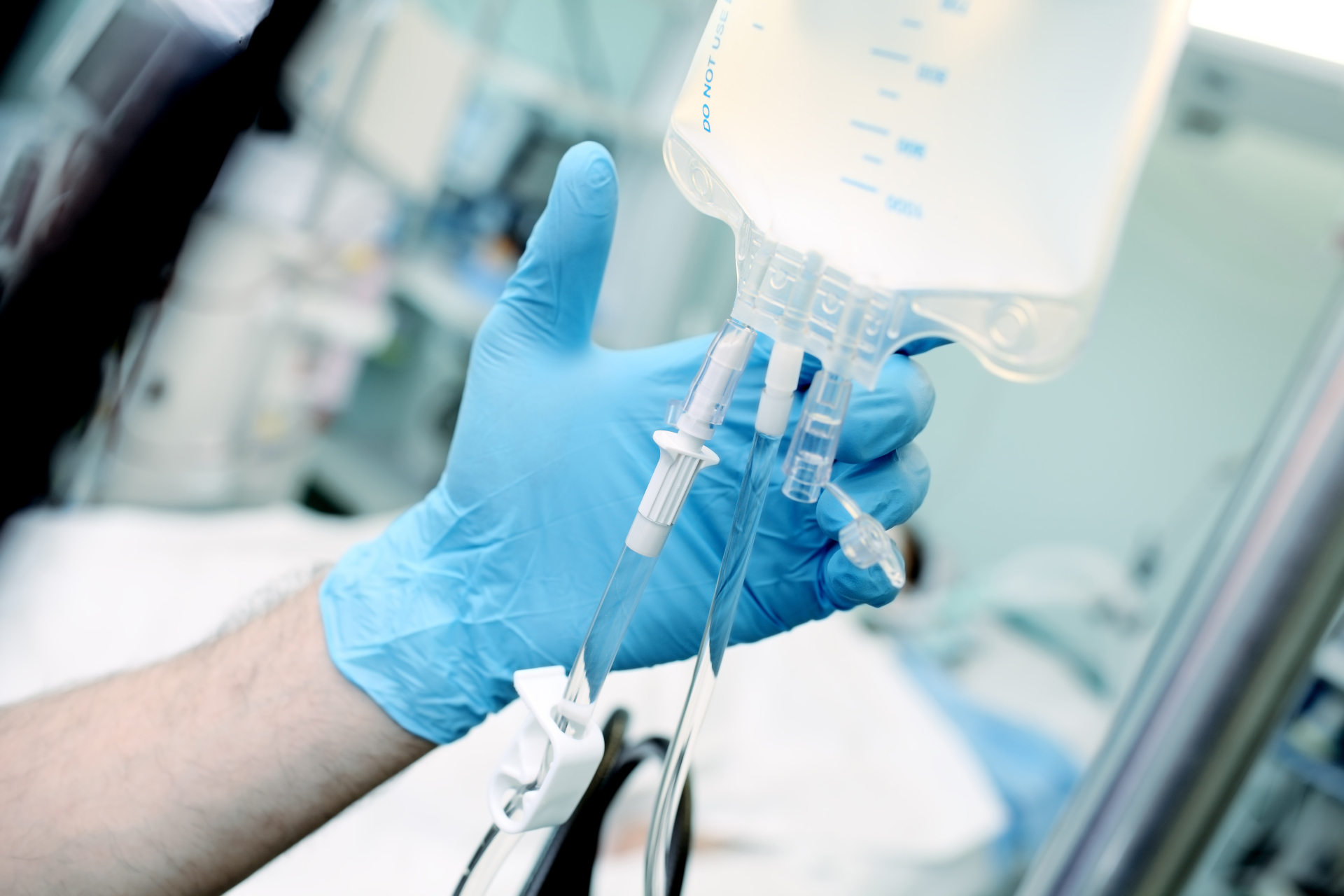 Male medical worker regulate the intravenous drip system at the patient bed in the critical care unit in Pasadena, CA