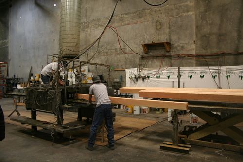 Employees loading staining machine with wood