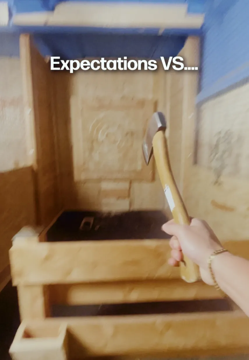 Persoon houdt een bijl vast voor een houten werpwand, met tekst 'Expectations VS....' in beeld.