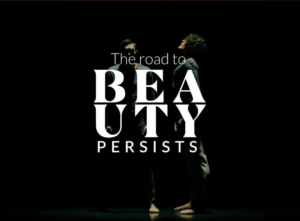 Twee dansers op een donker podium, met de tekst 'The road to BEAUTY PERSISTS' prominent in beeld.