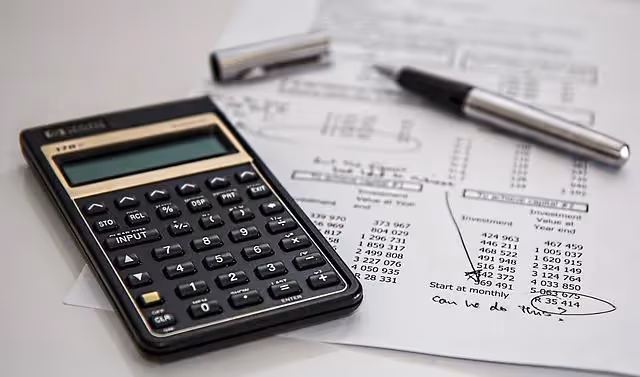 Calculator and pen placed on top of printed financial statements.