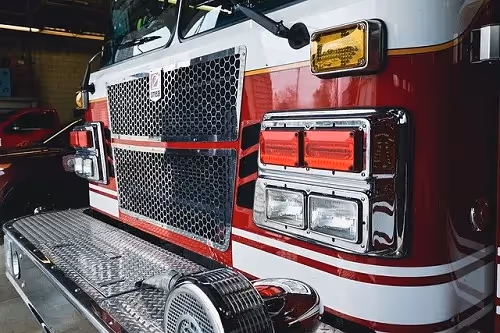 Close-up of a fire truck’s front grille, lights, and metal step platform.
