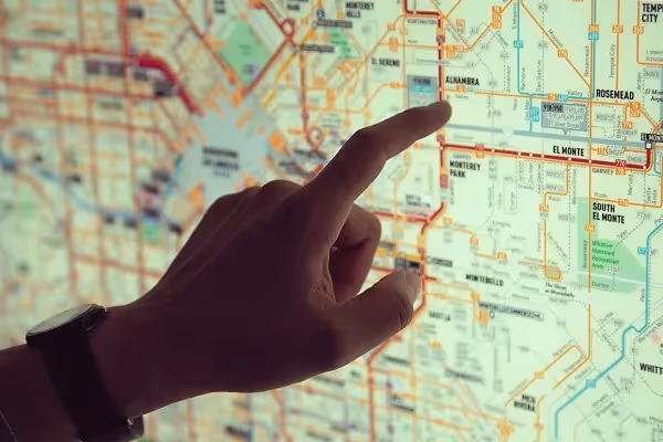 Hand pointing at a detailed transit or city map on a backlit display.