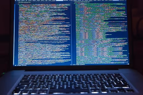 Laptop screen displaying dense lines of colorful programming code.