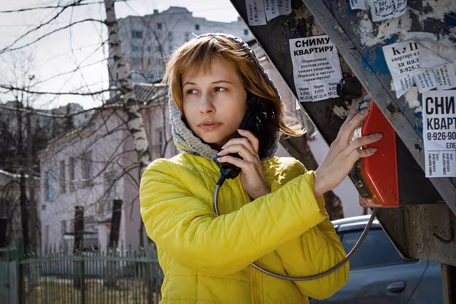 woman sing landline public phone to make international call