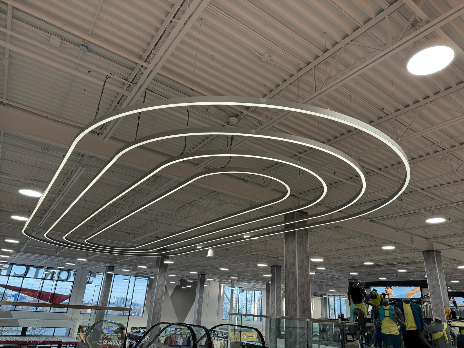 Sport Chek Etobicoke store interior with Cence Class 2 low-voltage DC centralized hubs powering modular linear suspension fixtures at four-story ceiling height.