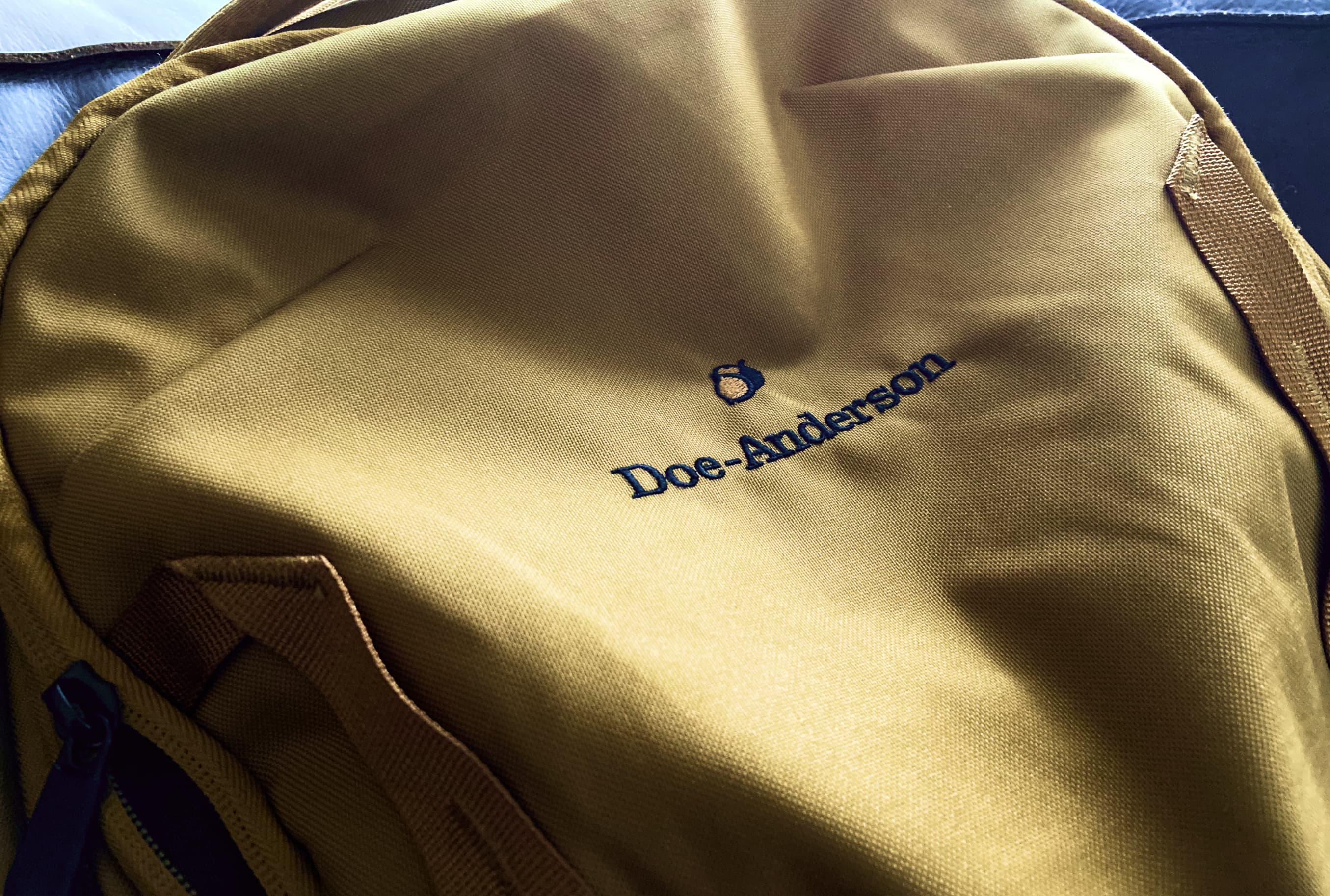 Doe-Anderson acorn logo on a tan canvas backpack.