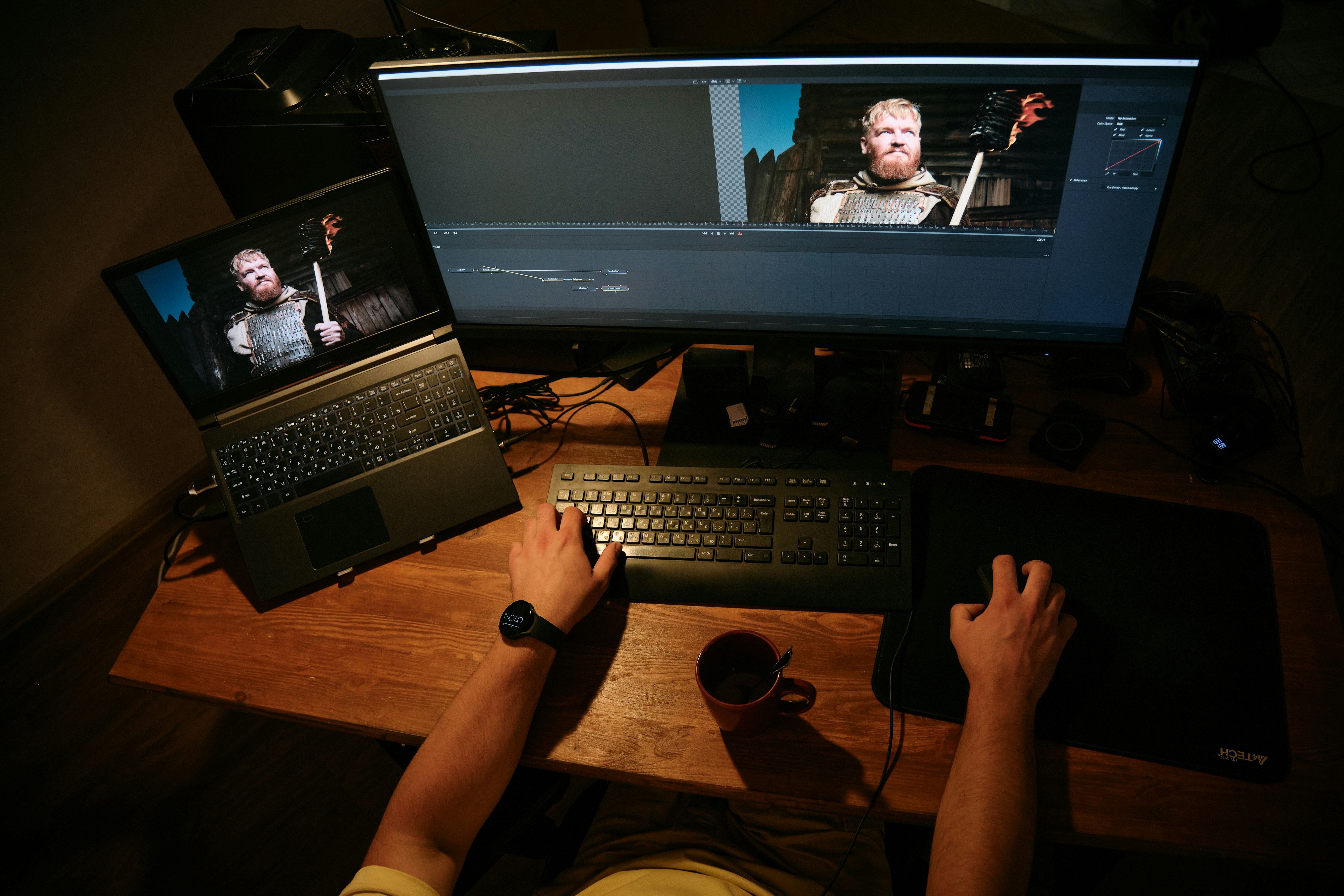 A person sits at a desk in editing video in front of two computer monitors. 