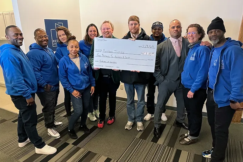 Smokeball employees deliver donation check to nonprofit partner "Restore Justice".