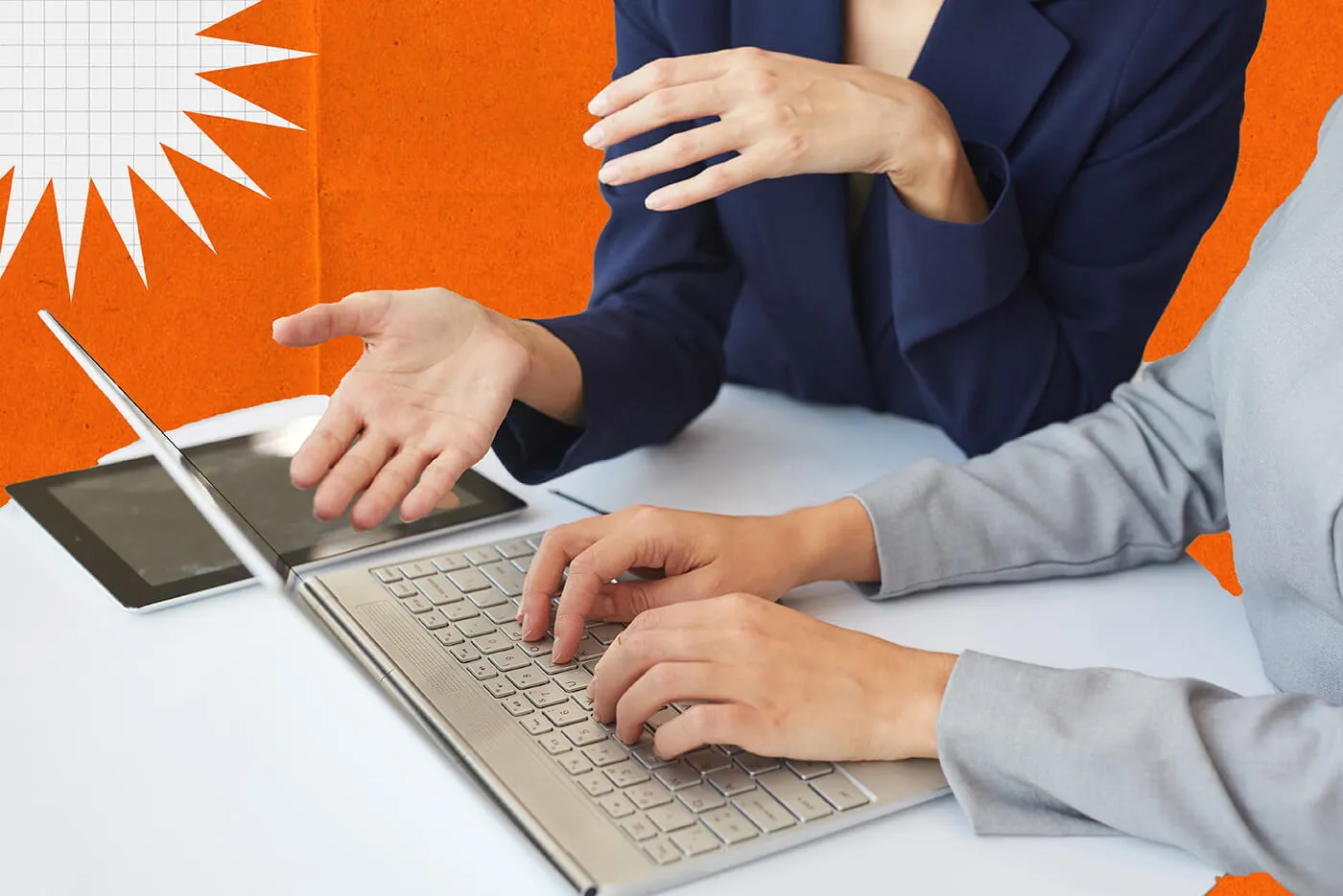 A bald man wearing a suit and woman with a blazer work at a desk with their phones and a tablet