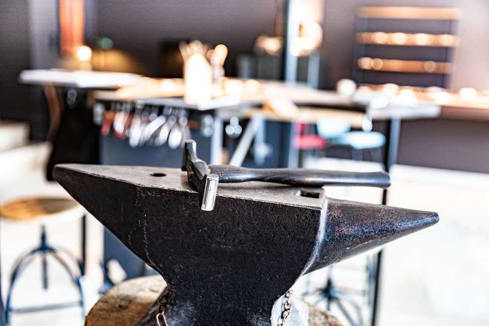 Blacksmith anvil with a small hammer resting on top in a workshop setting.