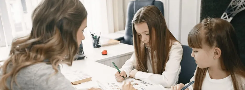 Niñera cuidando a niños dentro de una casa.