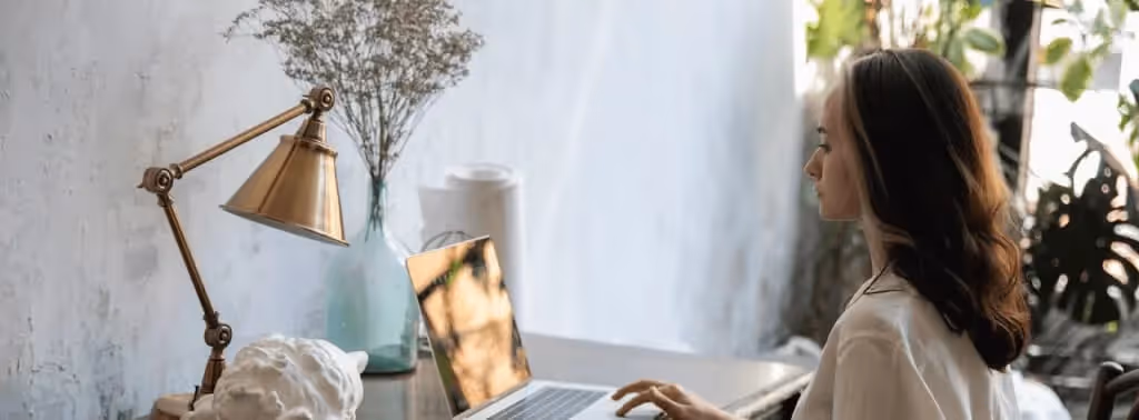 Mujer trabajando desde una computadora en casa.