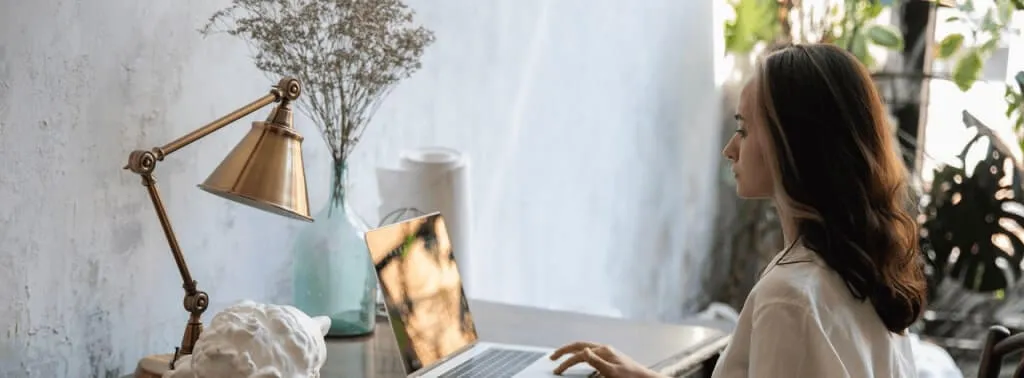 Mujer trabajando desde una computadora en casa.
