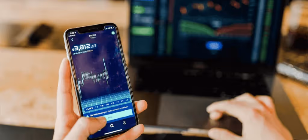 Mano sosteniendo celular con una pantalla que presenta una gráfica de inversión