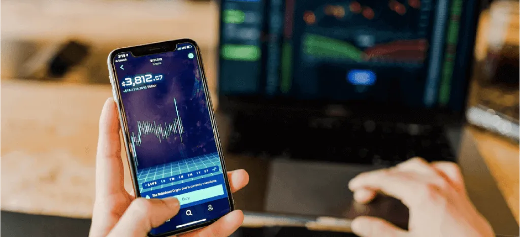 Mano sosteniendo celular con una pantalla que presenta una gráfica de inversión